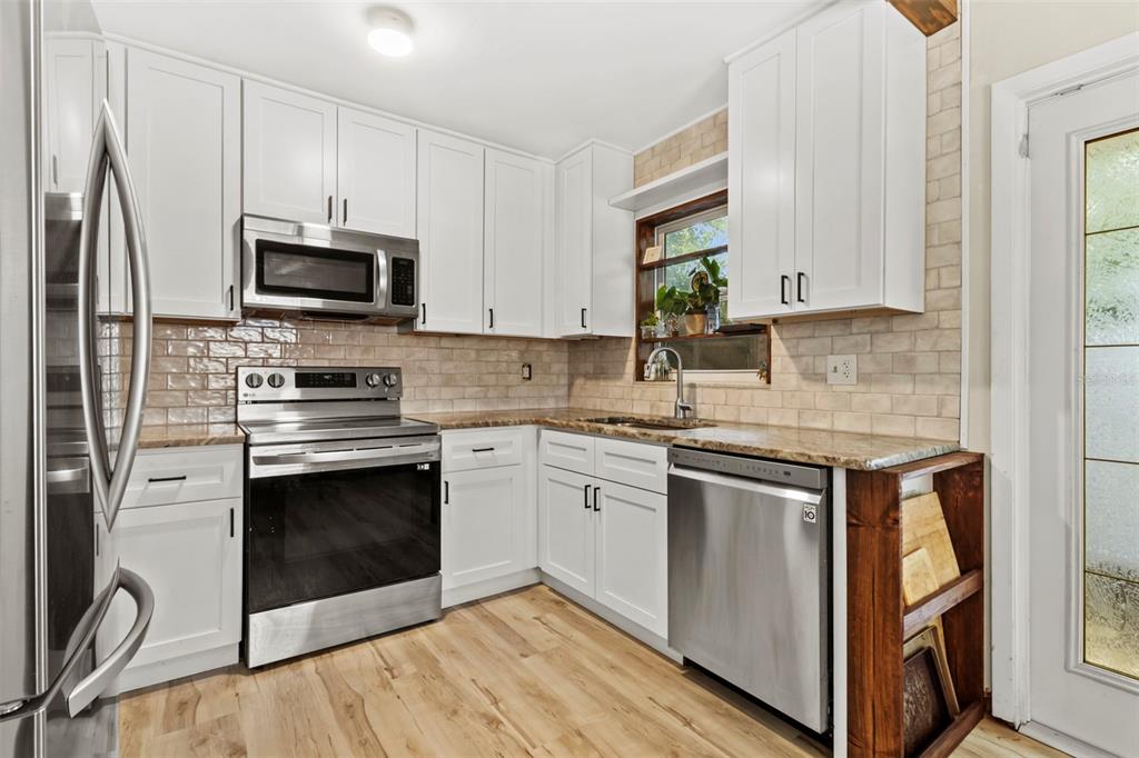 6221 Dalton Street Spring Hill, FL 34606 - Photo 4 of 40 a kitchen with stainless steel appliances granite countertop a stove a sink and a microwave
