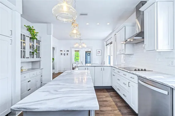 a large white kitchen with stainless steel appliances granite countertop a lot of counter space and wooden floor