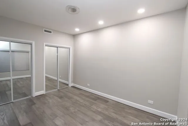 an empty room with wooden floor and mirror