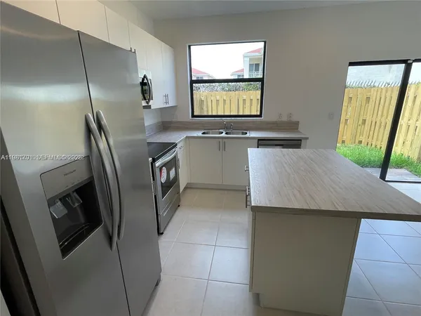 a kitchen with stainless steel appliances granite countertop a refrigerator a sink a stove and island