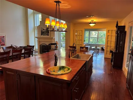 a kitchen with stainless steel appliances granite countertop a sink a stove top oven a dining table and chairs with wooden floor