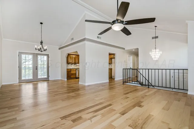 a view of an empty room with wooden floor and a ceiling fan