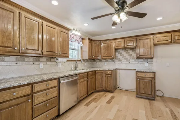 a kitchen with stainless steel appliances granite countertop a sink cabinets and wooden floor