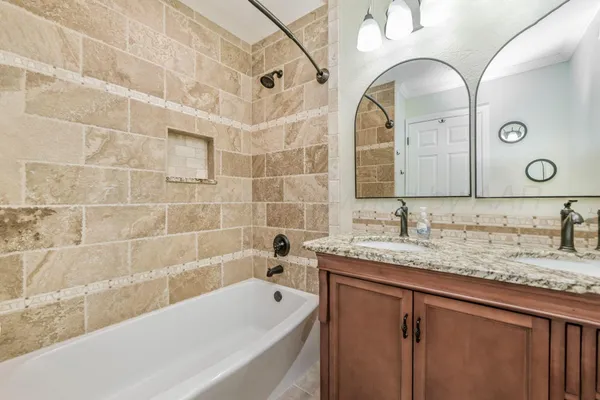 a bathroom with a granite countertop sink a mirror a bathtub and shower