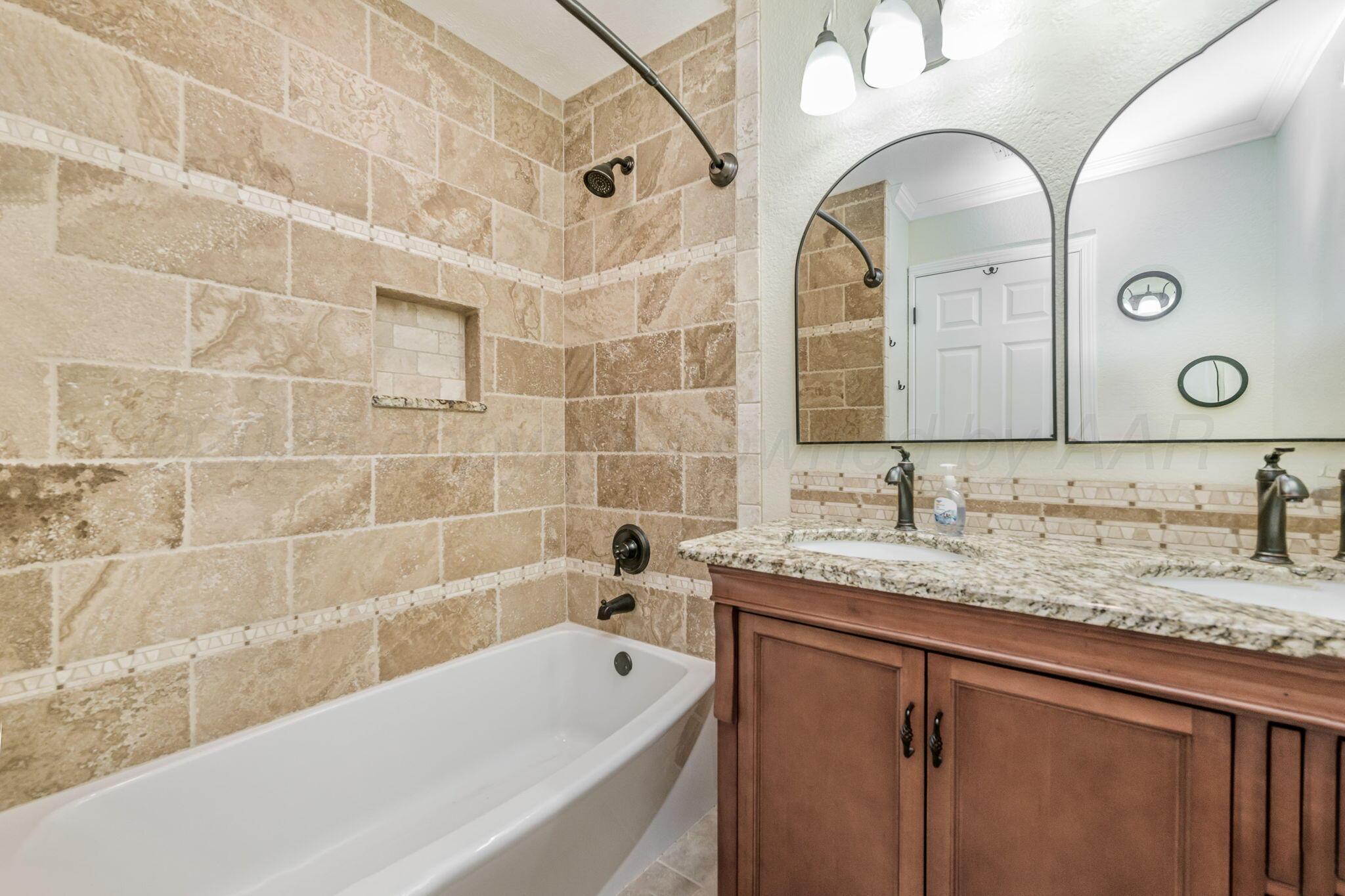 101 Mathis Drive Amarillo, TX 79118 - Photo 19 of 36 a bathroom with a granite countertop sink a mirror a bathtub and shower