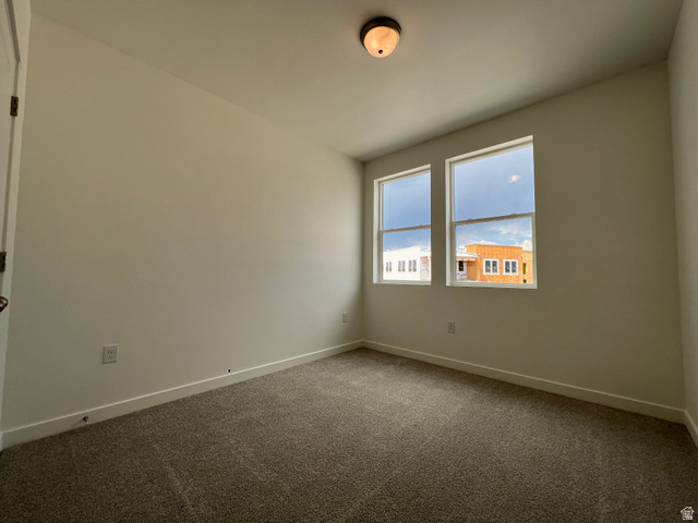 717 West W Coho Lane South, Unit 2F302 Midvale, UT 84047 - Photo 14 of 22 Neutral wall color, two windows, textured carpet, white baseboards, and a ceiling-mounted light fixture