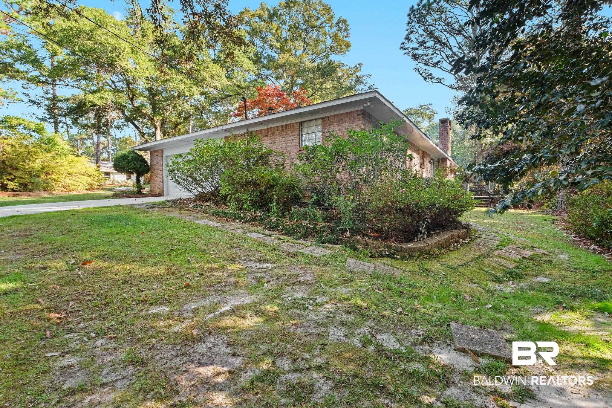 752 Evergreen Street Fairhope, AL 36532 - Photo 76 of 100 View of property exterior featuring brick siding, a chimney, a lawn, and an attached garage