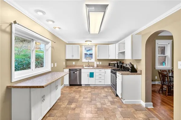 a white kitchen with a window a sink and a refrigerator