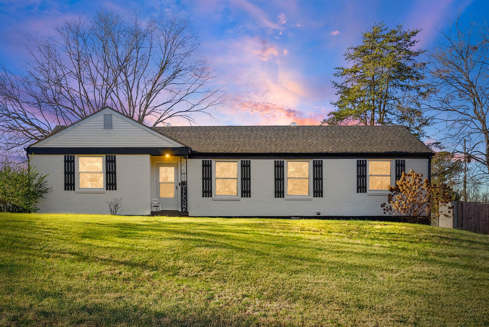 a front view of house with yard and trees in the background