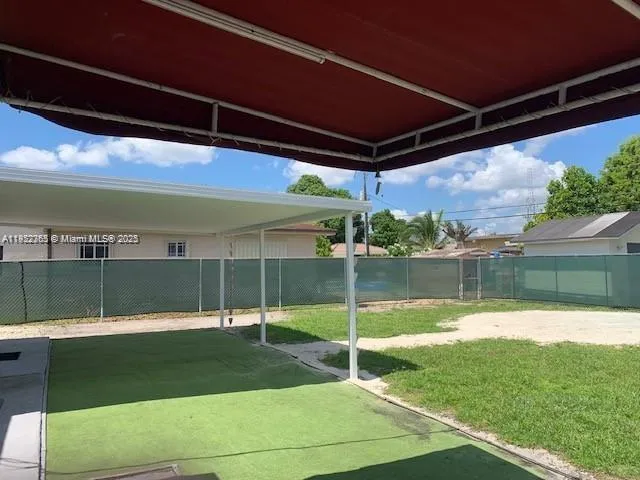 a view of a house with a yard and a large tree