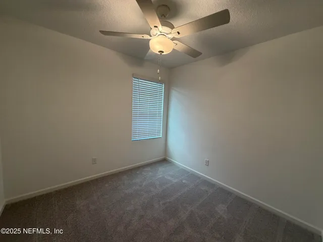 an empty room with a window and a fan