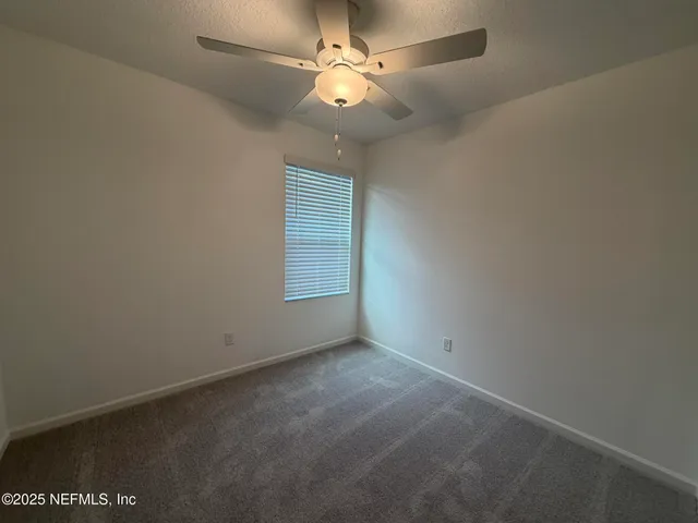 an empty room with a window and a fan