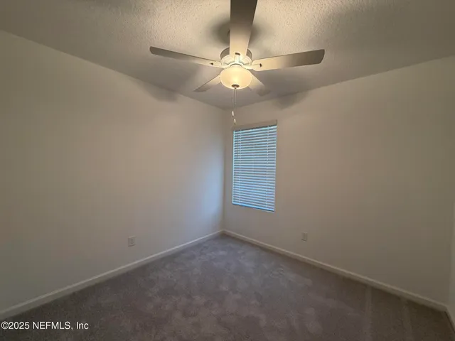 an empty room with a fan & windows