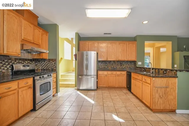 a kitchen with stainless steel appliances granite countertop a refrigerator and a stove top oven