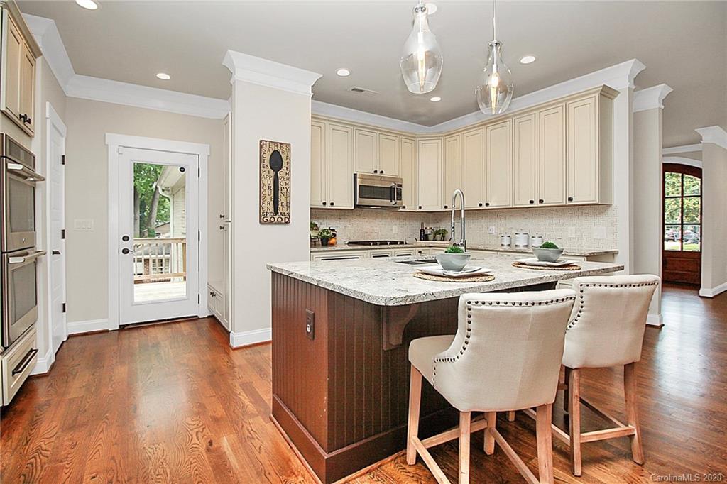 132 Scofield Road Charlotte, NC 28209 - Photo 16 of 44 a kitchen with stainless steel appliances granite countertop a stove top oven a refrigerator a sink and a dining table with wooden floor