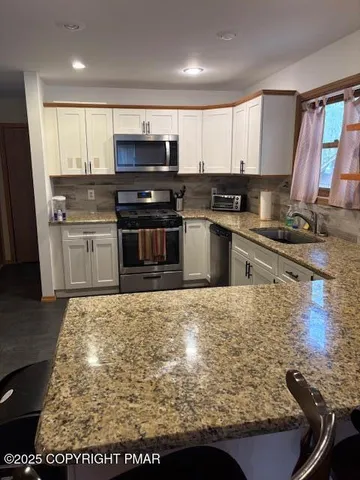a kitchen with kitchen island granite countertop a sink counter top space appliances and cabinets