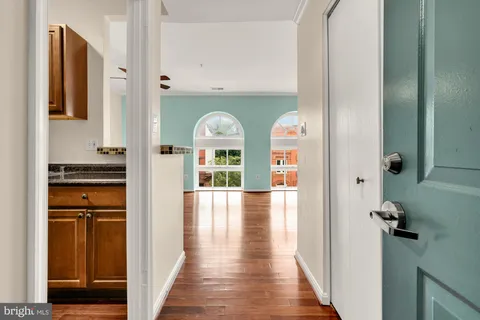 a view of a hallway with wooden floor windows and a living room