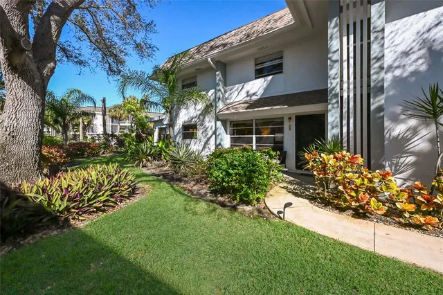 a front view of house and yard with beautiful flowers