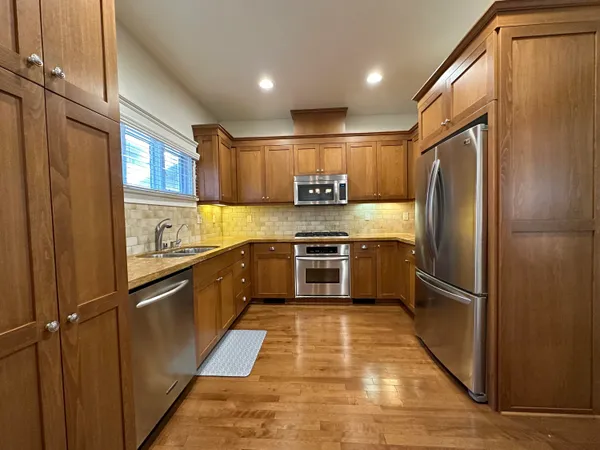a kitchen with granite countertop stainless steel appliances a refrigerator and cabinets