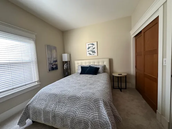 a bedroom with a bed and a dresser next to a window