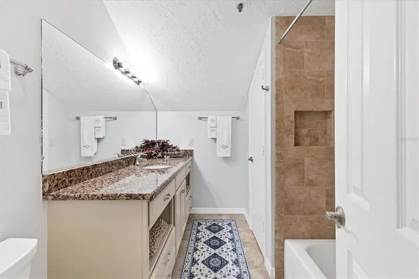 a en suite bathroom with a granite countertop sink and a mirror