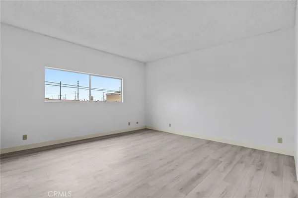 a view of an empty room with wooden floor and closet