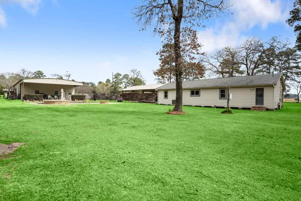 a view of a house with a big yard and large trees