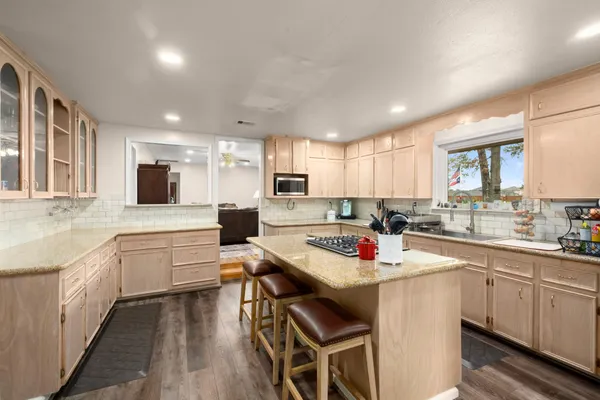 a kitchen with a stove a sink dishwasher a refrigerator and white cabinets with wooden floor