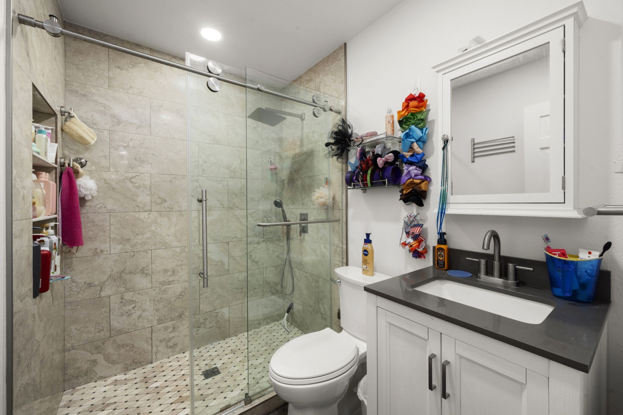 26136 Joseph Road Hockley, TX 77447 - Photo 25 of 31 Modern bathroom #2 featuring a spacious glass-enclosed shower with tiled walls, sleek vanity with a dark countertop, wall-mounted storage, and contemporary fixtures.