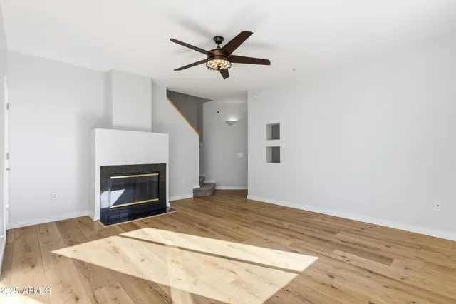 a view of empty room with wooden floor and fan
