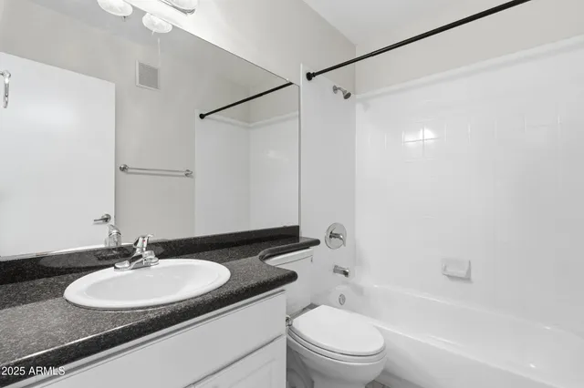 a bathroom with a granite countertop sink toilet a mirror and shower