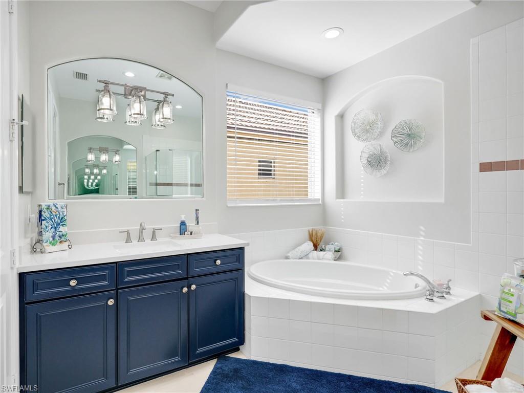 6096 Dogleg Drive Naples, FL 34113 - Photo 35 of 49 a bathroom with a tub double sink and mirror