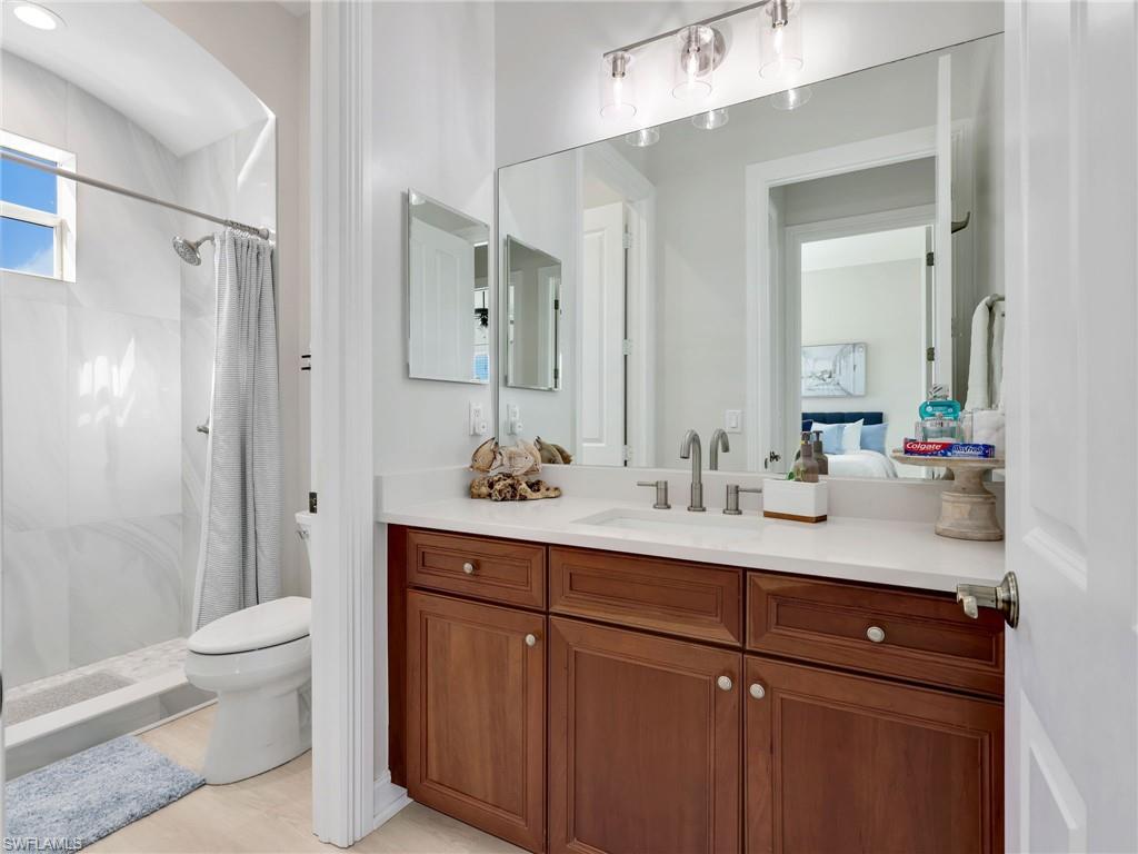 6096 Dogleg Drive Naples, FL 34113 - Photo 41 of 49 a bathroom with a sink a toilet a large mirror and shower