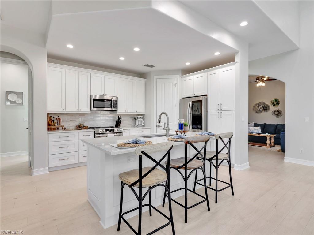 6096 Dogleg Drive Naples, FL 34113 - Photo 5 of 49 a kitchen with cabinets and chairs