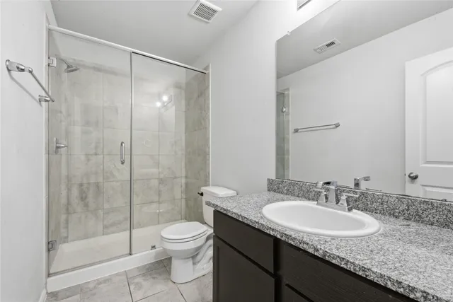 a bathroom with a granite countertop sink a toilet and shower