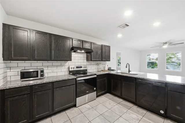a kitchen with stainless steel appliances granite countertop a sink dishwasher stove top oven and wooden cabinets