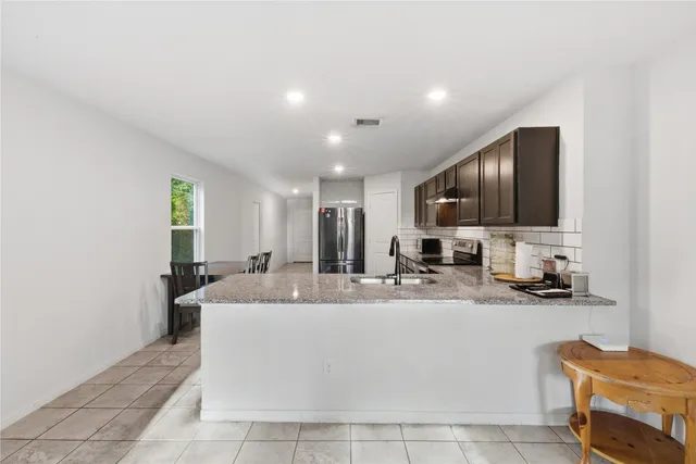 a large white kitchen with a sink and a large mirror next to a window