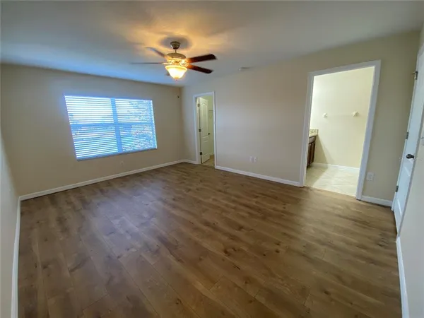 a view of an empty room with wooden floor and a window