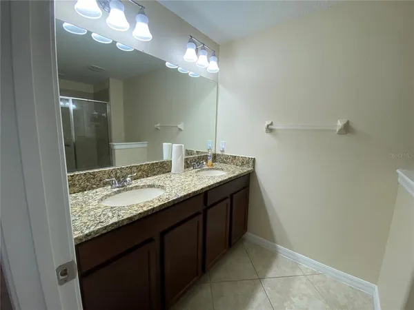 a bathroom with a granite countertop sink a large mirror and a shower