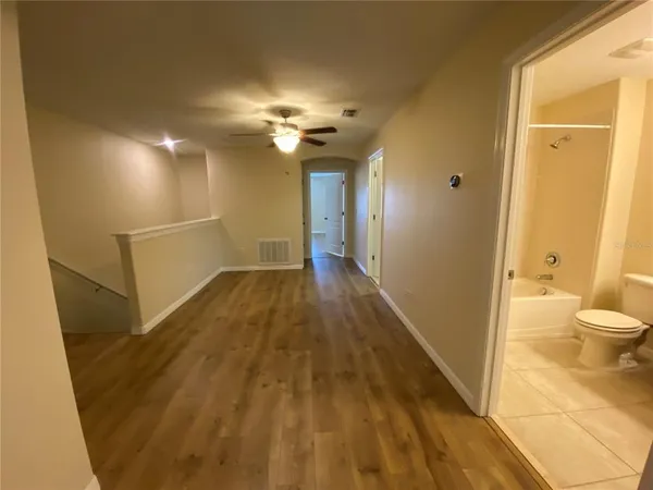 a view of a hallway with wooden floor and a bathroom