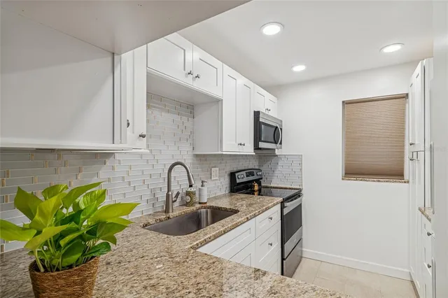 a kitchen with stainless steel appliances granite countertop a sink a stove and a refrigerator