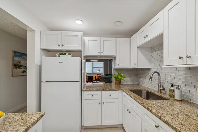 a kitchen with refrigerator a stove a sink and white cabinets