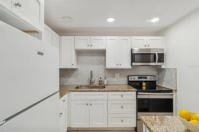 a kitchen with granite countertop white cabinets and stainless steel appliances