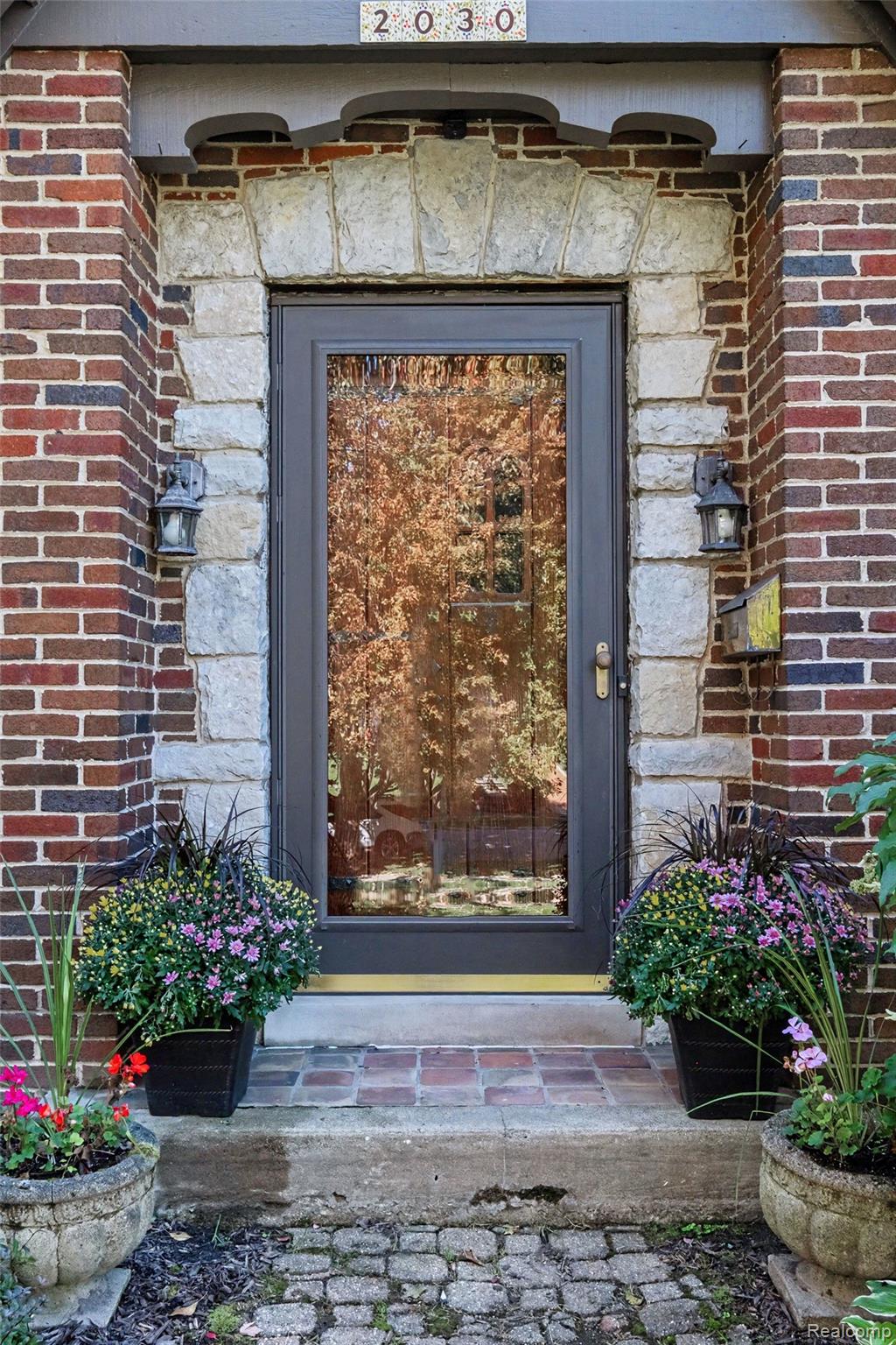 2030 Hampden Road Flint, MI 48503 - Photo 3 of 34 Brick exterior featuring a stone archway, glass-paneled entry door, and exterior wall sconces
