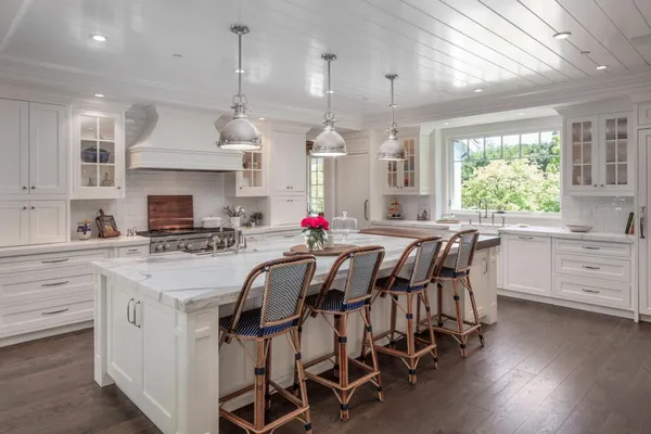 a kitchen with stainless steel appliances kitchen island wooden floors and white cabinets