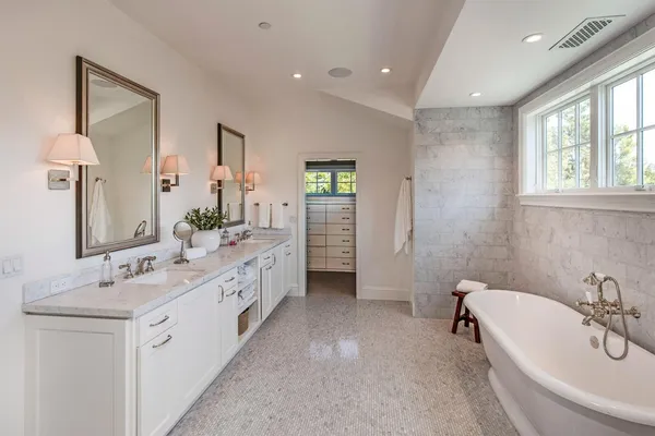 a spacious bathroom with a double vanity sink a mirror and a bathtub