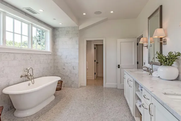 a spacious bathroom with a tub sink and a mirror