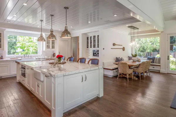 a kitchen with stove a dining table chairs wooden floors and a large window