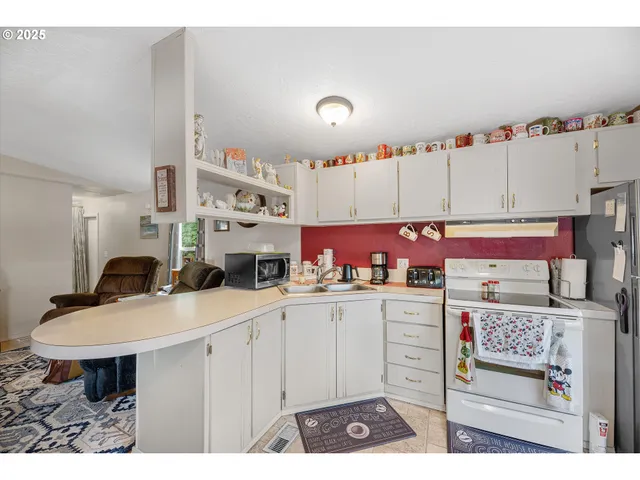 a kitchen with stainless steel appliances kitchen island granite countertop a table chairs and a refrigerator