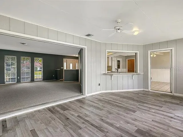 a view of a livingroom with wooden floor and kitchen space